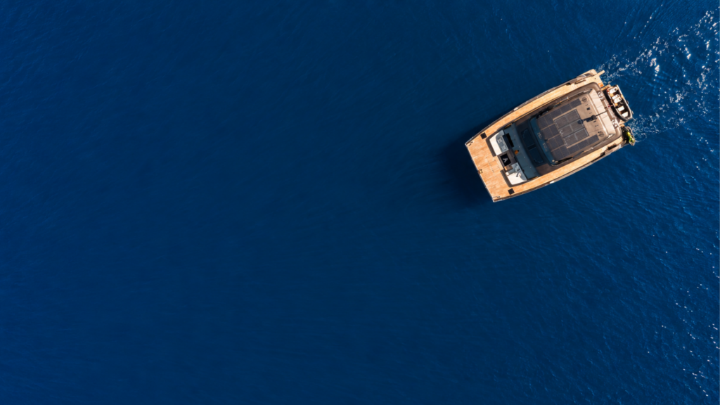A catamaran captured from above, gliding on the deep blue sea.